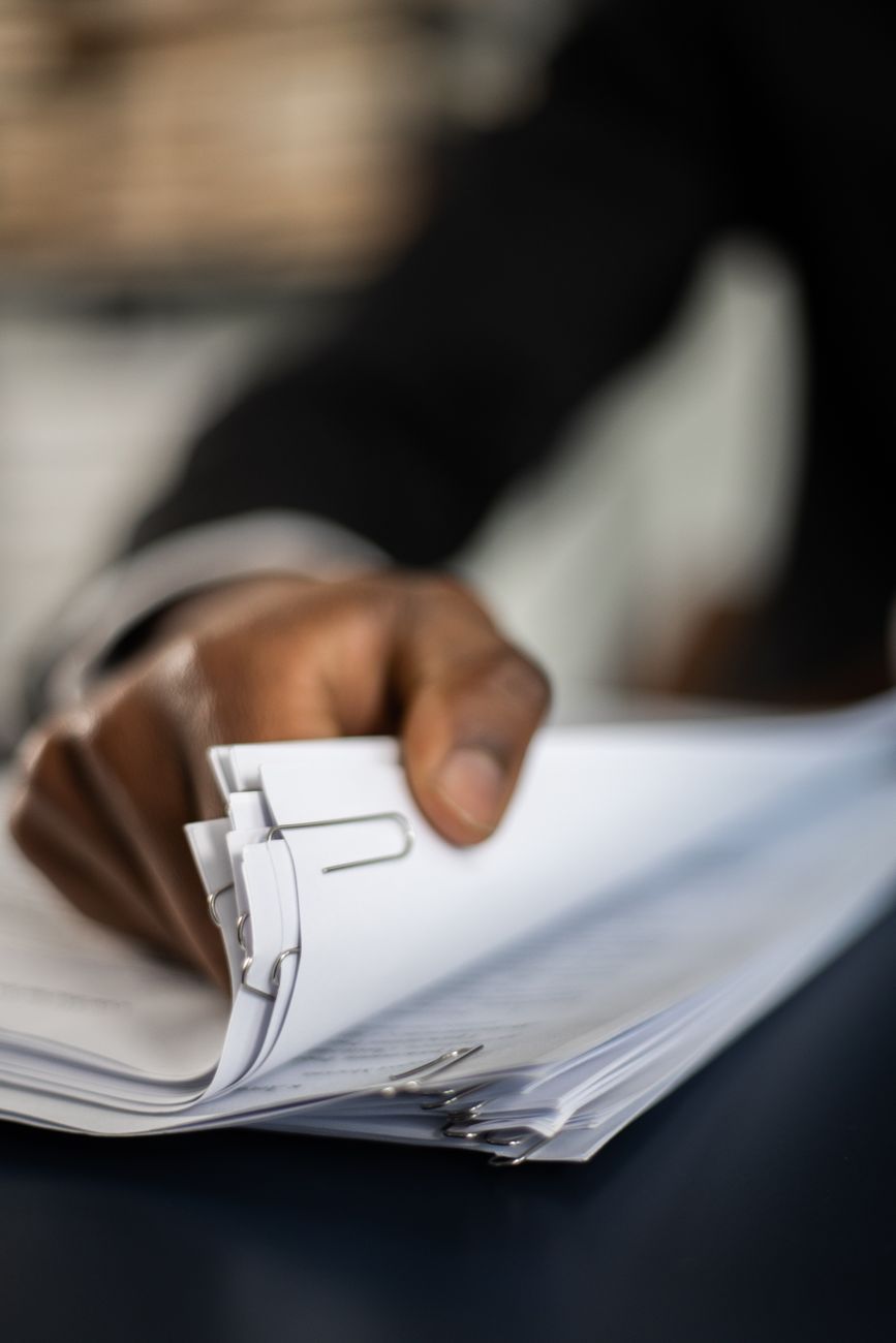 A hand organizing a stack of documents with paper clips